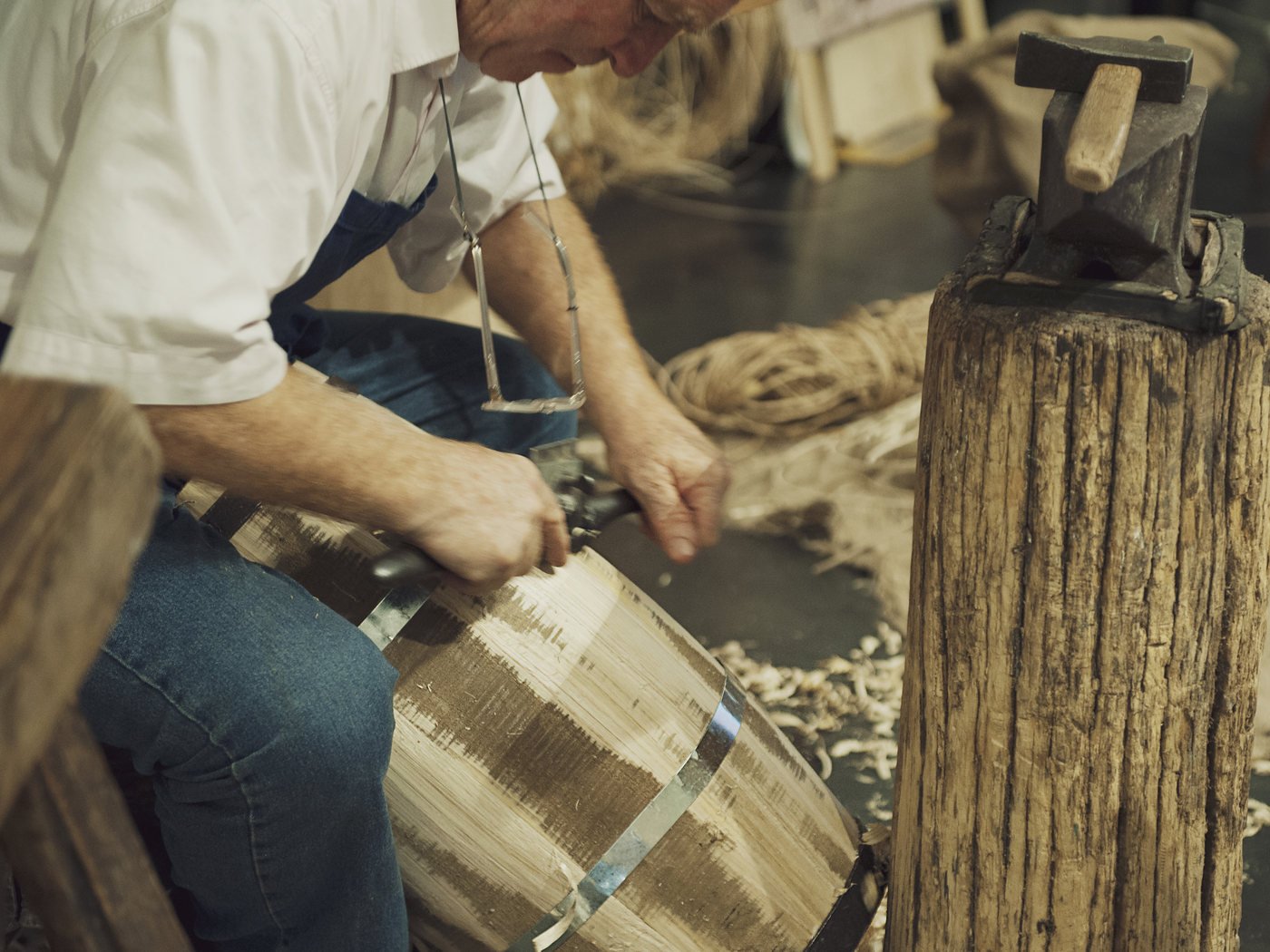 Un bottaio cerchia una botte di legno nella sua bottega