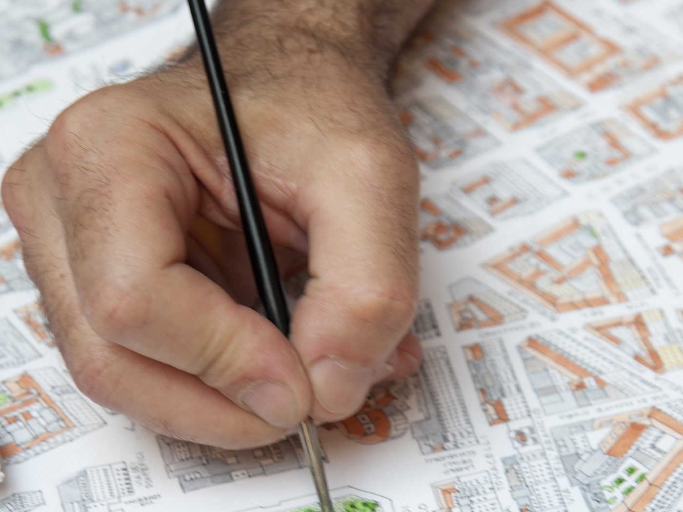Una mano dipinge a pennello una delle mappe illustrate di Botteghiamo